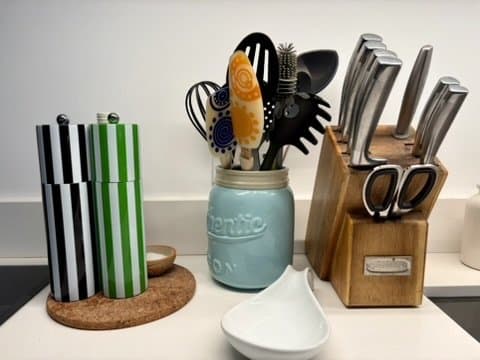 Black-and-white and green-and-white striped salt and pepper mills on a cork coaster on a kitchen counter